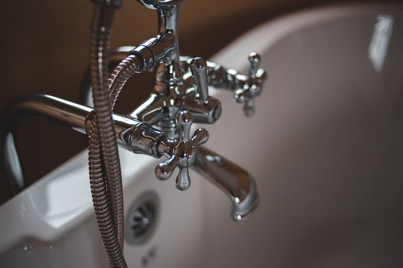 Licensed plumber repairing a leaking pipe connection in a residential wall